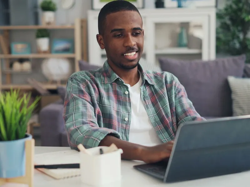 Homem sorrindo enquanto usa o notebook em casa